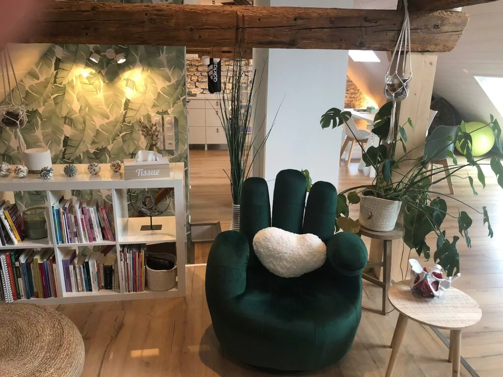 Espace détente dans le cabinet principal, avec un fauteuils vert et une décoration apaisante.